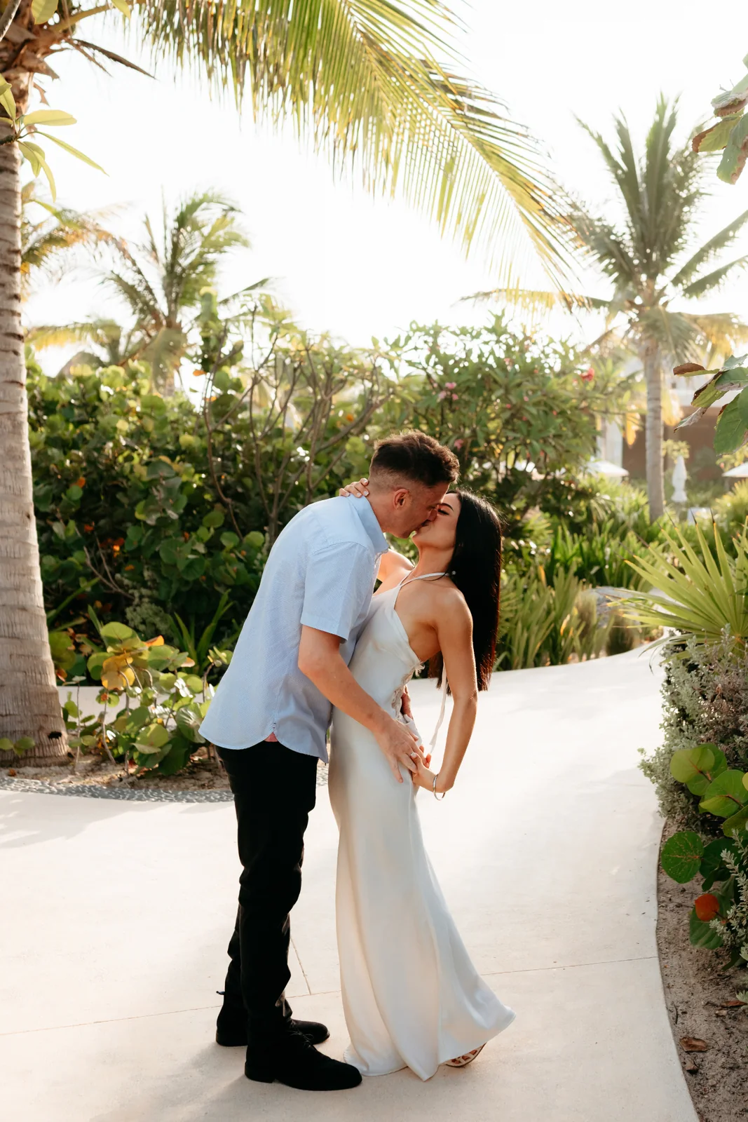 Craig and Angela kissing beneath palm trees