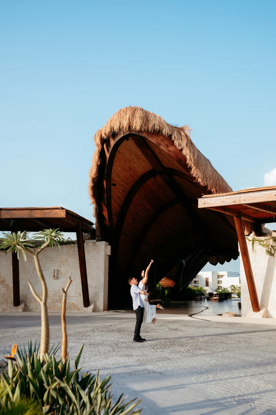 Craig lifting Angela beneath a thatched palapa